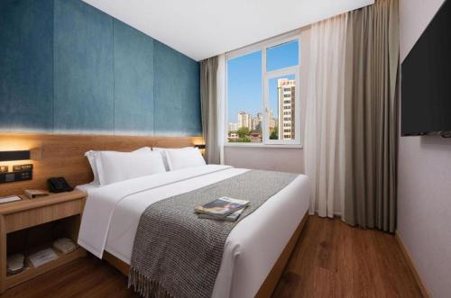 a bedroom with a large bed and a window at New Beacon Sunyee SPA Hotel in Wuhan