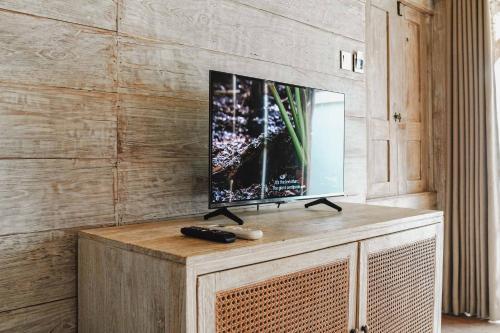 a flat screen tv on top of a wooden entertainment center at Java Wood in Gili Trawangan