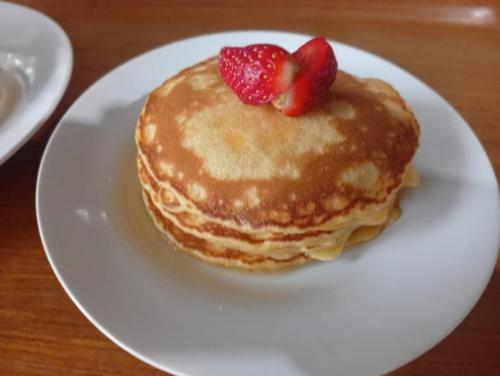 a plate with a stack of pancakes with strawberries on it at Benabilla Cottage 