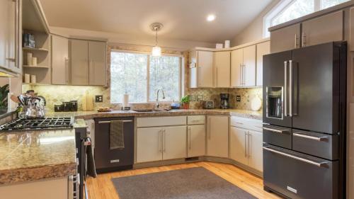 a kitchen with white cabinets and a black refrigerator at River Meadows by AvantStay Near River w Hot Tub Access to Private Boat Ramp in Bend