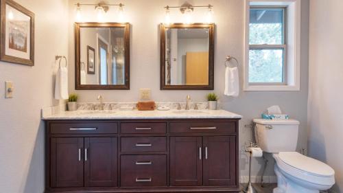 a bathroom with a sink and a toilet and mirrors at River Meadows by AvantStay Near River w Hot Tub Access to Private Boat Ramp in Bend