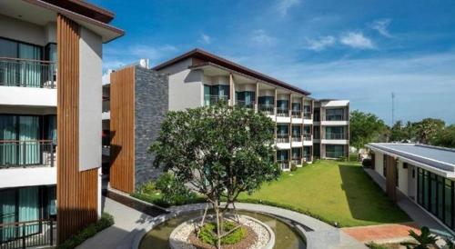 an apartment building with a tree in the courtyard at i Tara Private in Phetchaburi