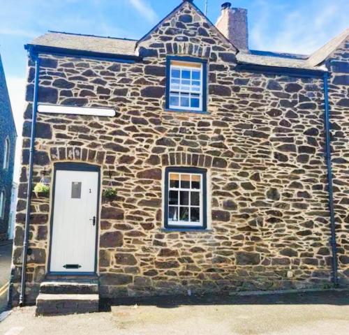 a stone building with a white door and windows at Characterful 2 bed within Conwy Walls in Conwy
