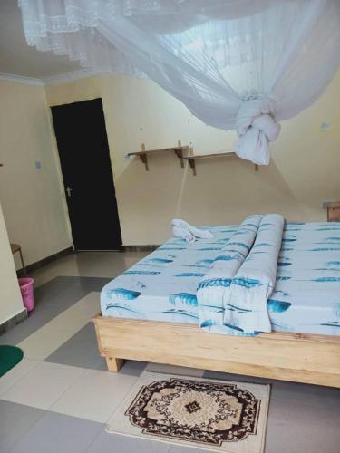 a bedroom with a bed with blue sheets and a window at Kakakuona Resort in Lushoto