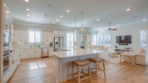 a kitchen with white cabinets and a large island with bar stools at Coconut Cove by AvantStay Deck w Hot Tub Access to 2 Pools in Santa Rosa Beach