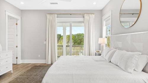 a white bedroom with a large bed and a mirror at Sea Dweller by AvantStay Rooftop Spa Gulf View Golf Cart Pool in Inlet Beach