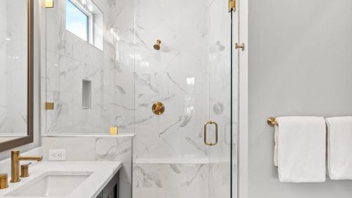 a white bathroom with a shower and a sink at Sea Dweller by AvantStay Rooftop Spa Gulf View Golf Cart Pool in Inlet Beach