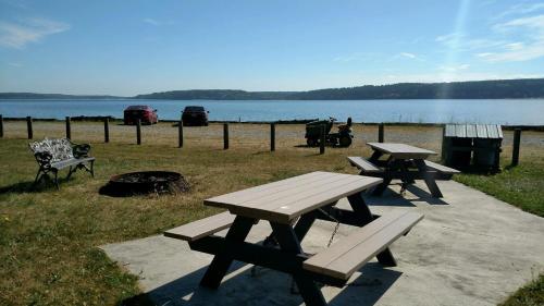 two picnic tables and a fire pit next to a lake at Harborview Getaway by AvantStay Walk to Beach in Langley