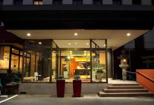 a building with two potted plants in front of it at Hotel 1-2-3 Kofu Shingen Onsen in Kofu