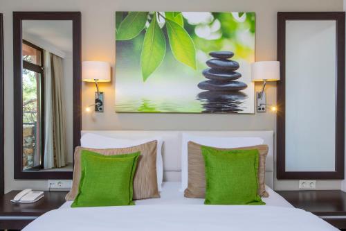 1 dormitorio con cama blanca y almohadas verdes en Bella Garden Hotel, en Bodrum City
