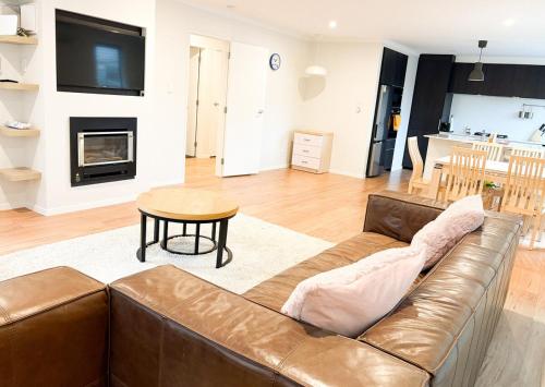 a living room with a brown leather couch and a table at Modern elegance Woburn 3 bedroom Retreat in Lower Hutt