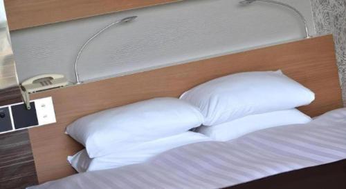a bed with white pillows in a hotel room at Green Hill Hotel Onomichi in Onomichi