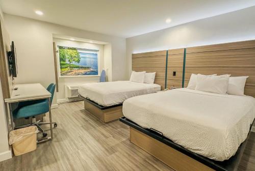 a hotel room with two beds and a chair at Baymont by Wyndham Henrietta - Rochester in Henrietta