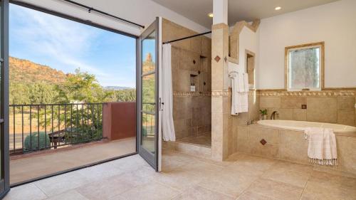 Un baño con bañera y ducha con ventana. en Mystic Sunset by AvantStay Thunder Mountain View Pool Driving Range Casita, en Sedona