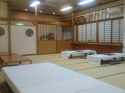 a room with two tables and benches in it at Hotel Honjin in Kumamoto