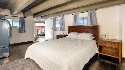 a bedroom with a large bed and a refrigerator at Skyline Lofts by AvantStay: a multi-level industrial-chic retreat in DTLA with rooftop views soaring ceilings steps to dining music culture in Los Angeles