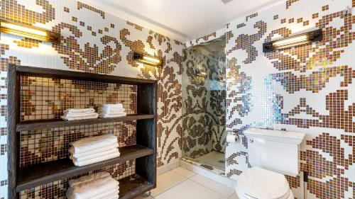 a bathroom with a toilet and a mosaic wall at Skyline Lofts by AvantStay: a multi-level industrial-chic retreat in DTLA with rooftop views soaring ceilings steps to dining music culture in Los Angeles