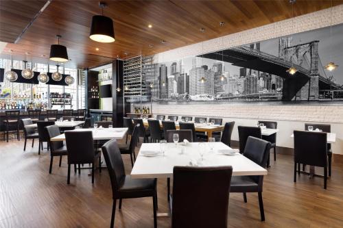 a restaurant with white tables and chairs and a bar at Hilton Garden Inn New York - Times Square Central in New York
