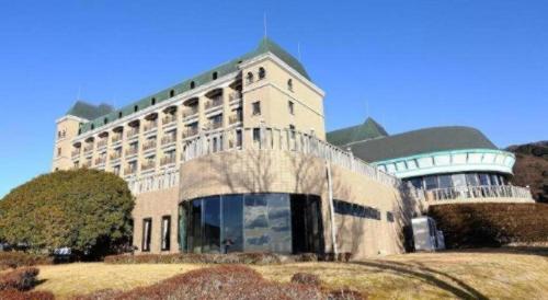 a large building on a hill with a grass field at HOTEL WINDSOR in Nakatsugawa