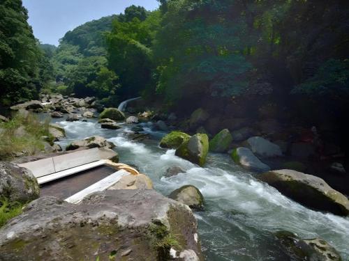 a river with rocks and trees in the background at Myoken Ishiharaso in Kirishima