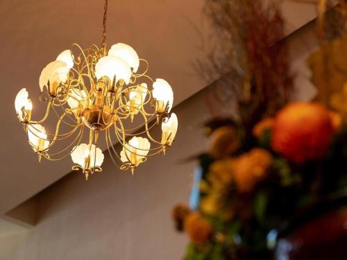a chandelier hanging from a ceiling with a vase of flowers at Yukemuri no sato azumaya in Beppu