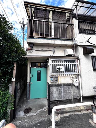 a building with a blue door in front of it at Osaka Riverside Inn in Neyagawa