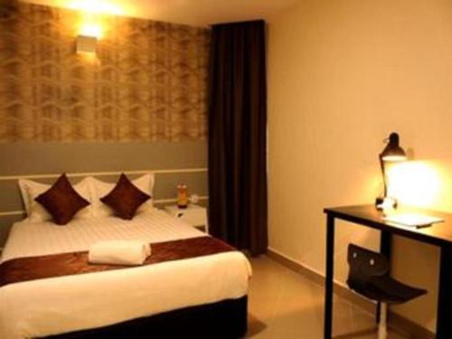 a hotel room with a bed and a desk with a lamp at Rock & Roll Hotel Klang in Klang