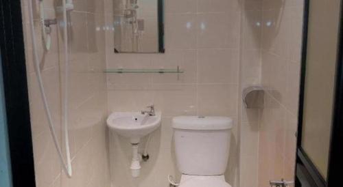 a white bathroom with a toilet and a sink at Power Hotel in Georgetown