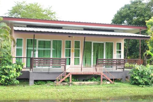 a house with two benches in front of it at ภูร์ชรินท์ รีสอร์ท in Ban Than Phra