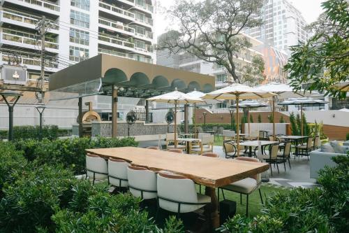 a wooden table with chairs and tables and umbrellas at Floral Court Hotel & Residence Sukhumvit 13 in Bangkok