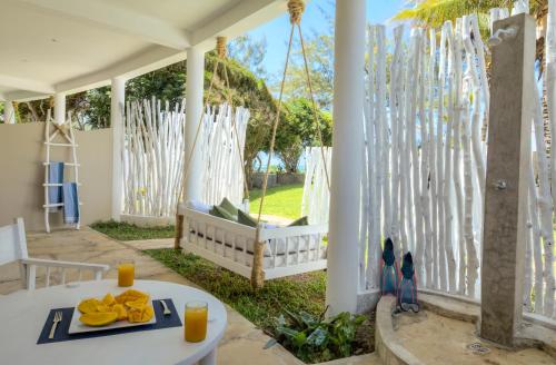 a white porch with a table with food on it at Kobe Suite Resort in Watamu