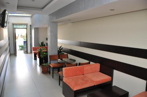 a waiting room with an orange couch and chairs at Sunrise Hotel Cameria in Durrës
