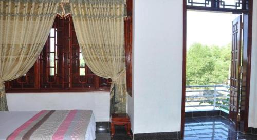 a bedroom with a bed and a large window at Anh Tuan Guest House in Hue