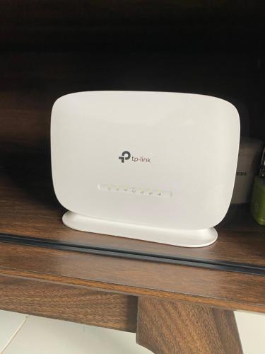 a white router sitting on a wooden table at Rumah Homestay in Kangar