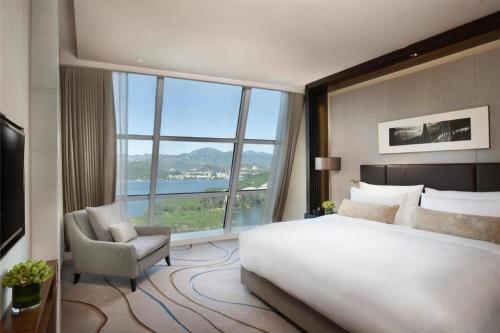una camera da letto con un grande letto e una sedia e una grande finestra di Sunrise Kempinski Hotel Beijing a Xizhuang