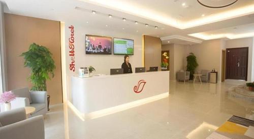 a woman standing at a counter in a lobby at Shell Changzhou Yangrong City Hotel in Changzhou