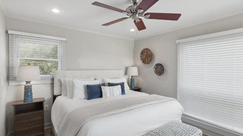 a bedroom with a white bed with a ceiling fan at Beach Retreat w Sundeck Golf Cart Bikes Bungalow House by AvantStay in Seacrest