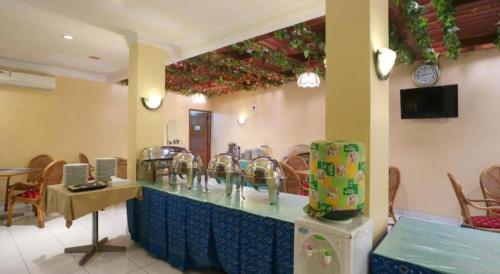 a restaurant with a counter with sinks and chairs at Hotel Permata Bandara in Jakarta