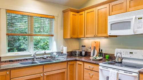a kitchen with wooden cabinets and a white appliance at The Cottage at Herons Roost by AvantStay in Langley