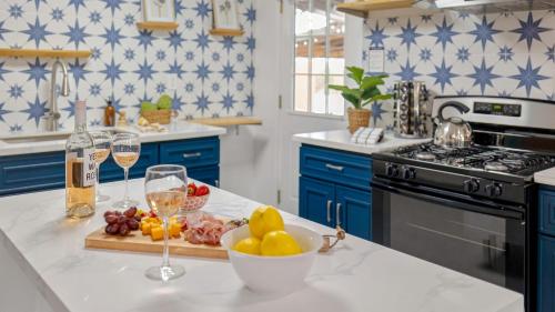 a kitchen with blue cabinets and a bowl of fruit and wine glasses at Fable by AvantStay 2 Unique Spaces w Bowling Hot Tub Fire Pit Large Yard in Joshua Tree