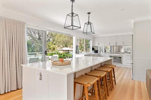 a kitchen with white cabinets and a large island with bar stools at Umina Beachside Getaway - Hot Tub - 5 Bedrooms in Umina