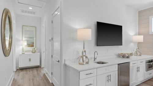 a white kitchen with a sink and a tv on the wall at Pool Hot Tub Firepit Golf Cart Included Walk to Beach Near Gulf Place in Santa Rosa Beach