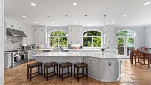 a kitchen with white cabinets and a island with bar stools at Flip Flop Therapy by AvantStay Lakefront Home w Game Room Dock Access in Mooresville