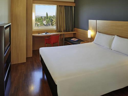 a bedroom with a bed and a desk and a window at ibis Sorocaba in Sorocaba