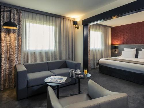 a hotel room with a bed and a couch at Mercure Paris Porte de Pantin in Pantin