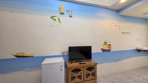 a room with a tv on a blue and white wall at Lang Jiao Ya She Homestay in Hengchun