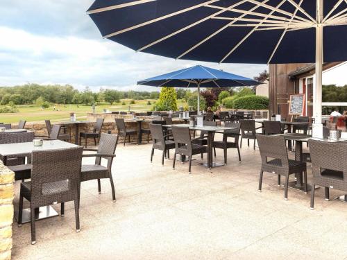 an outdoor patio with tables and chairs and umbrellas at Mercure Luxembourg Kikuoka Golf & Spa in Canach