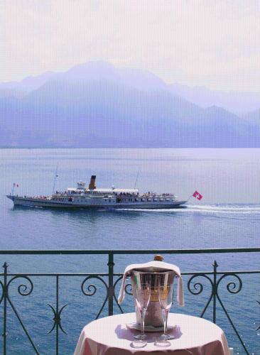a vase on a table with a boat in the water at Hotel Eden Palace au Lac in Montreux