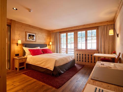 a bedroom with a bed with red pillows at Hotel Le Grand Chalet Gstaad in Gstaad