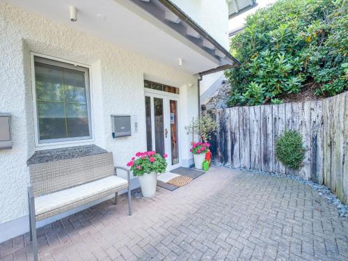een bankje buiten een huis met bloemen bij Modern Apartment in Schwalefeld with Garden in Willingen